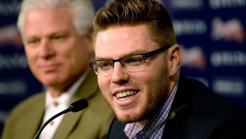 Atlanta Braves first baseman Freddie Freeman, sitting next to Braves General manager Frank Wren, announces that he has agreed to terms with the team that will keep him in a Braves uniform for eight years, on Wednesday, Feb. 5, 2014, in Atlanta.
