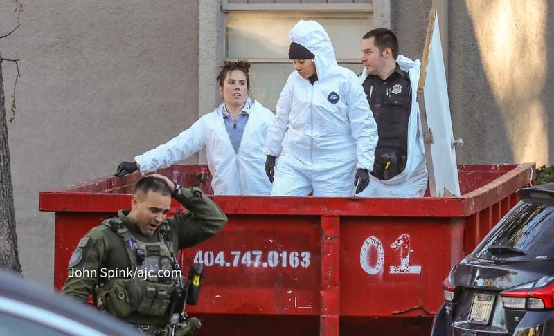 Crime scene investigators sift through a dumpster at the scene of a shooting in Stonecrest.