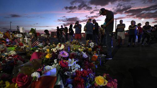 El Paso, Texas — Antonio Basco stands silently at his wife’s cross as family members visit the memorial site at dusk after funeral services that day for mass shooting victim Margie Reckard. (Carol Guzy/ZUMA Wire/TNS)