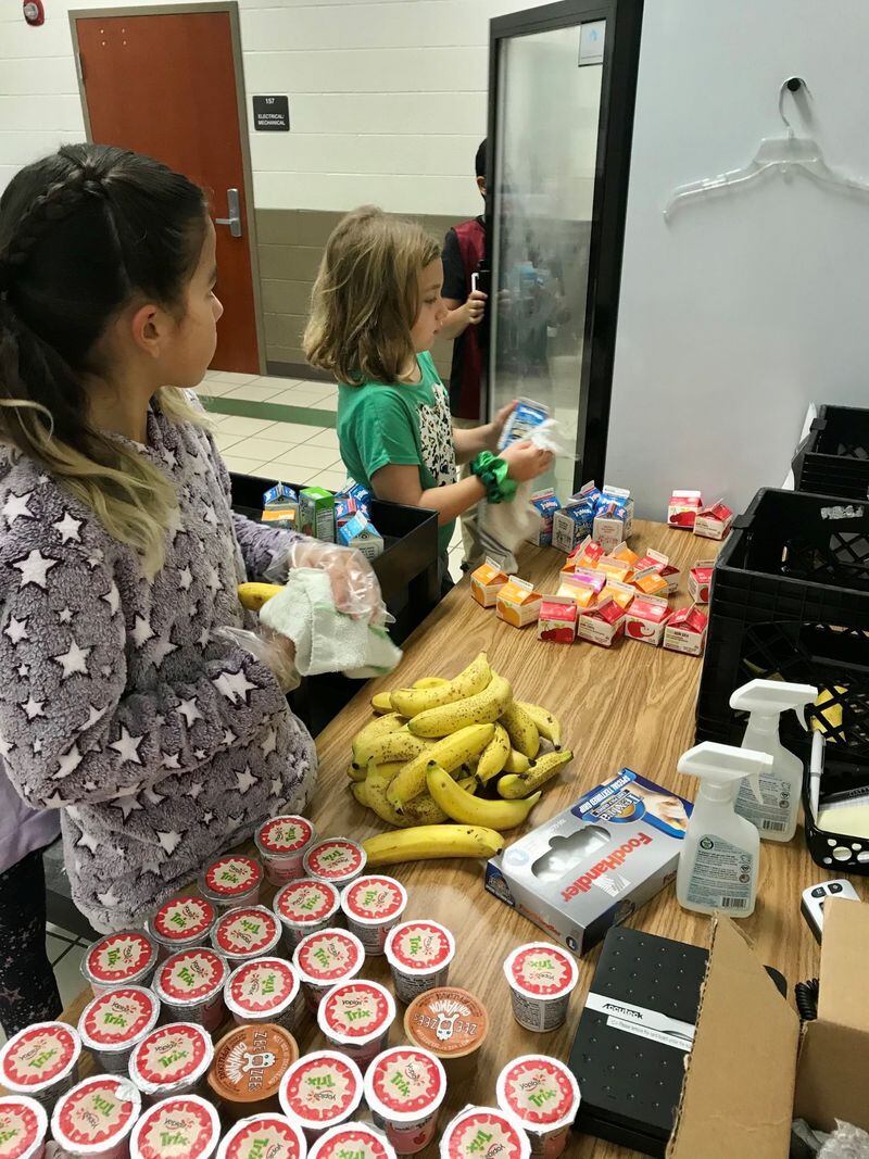 Kelly Mill Elementary students, from left, Ana and Ava wipe down donated food items before storing them in the refrigerator. Courtesy of Kelly Mill Elementary School