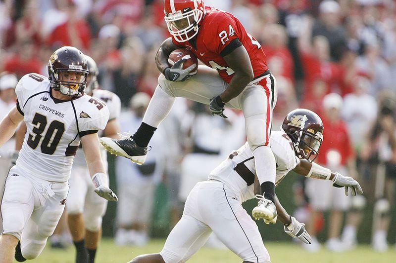 Georgia's Knowshon Moreno (24) leaps over Central Michigan defenders Mike Petrucci (30) and Vince Agnew (22) on a long run Saturday, Sept. 6, 2008, at Sanford Stadium in Athens.