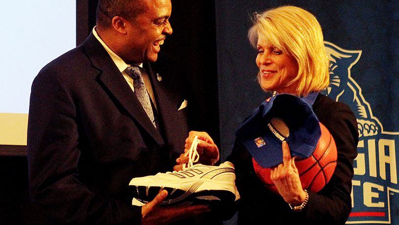 Georgia State Athletic Director Cheryl Levick (right) gives new basketball coach Ron Hunter a pair of shoes, basketball and a GSU hat during his introductory press conference in the school student center March 21, 2011, in Atlanta.