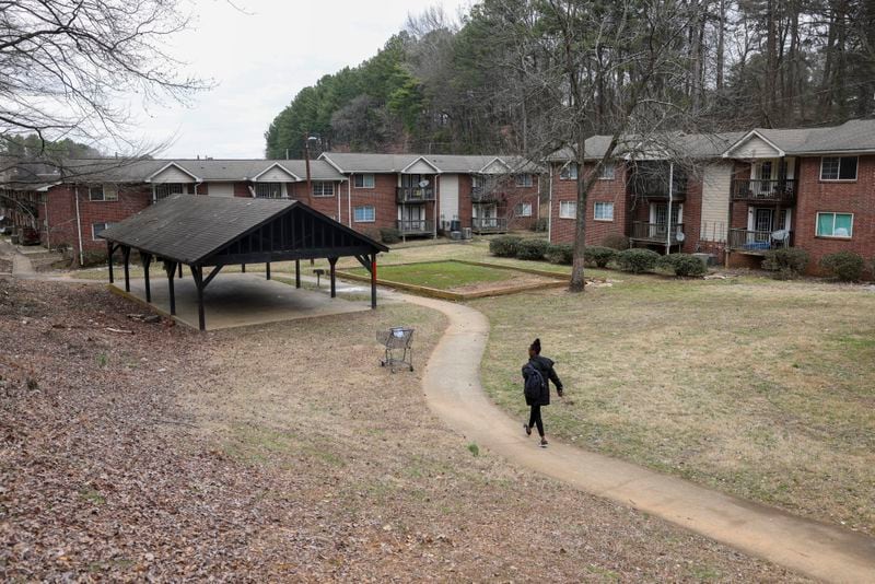 A woman walks in February toward an empty patch of grass where a playground used to stand at Pavilion Place apartments. The worn-out equipment was dismantled after a crackdown on conditions at the complex. (Jason Getz/Jason.Getz@ajc.com)
