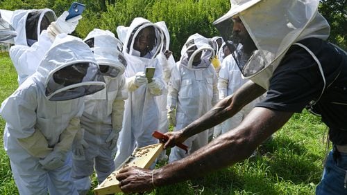 William Crumpler II, known as “Bill the Bee Man”, shows a section of a bee hive during an educational event to learn harvesting honey and beekeeping at Metro Atlanta Urban Farm, Thursday, July 6, 2023, in College Park. (Hyosub Shin / Hyosub.Shin@ajc.com)