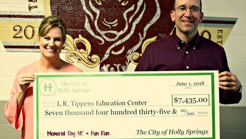 L.R. Tippens Education Center Principal Kelly Strickland (left) receives a check for $7,435 from Holly Springs Mayor Steven Miller, the net proceeds of the city’s Memorial Day 5K and Fun Run. CITY OF HOLLY SPRINGS