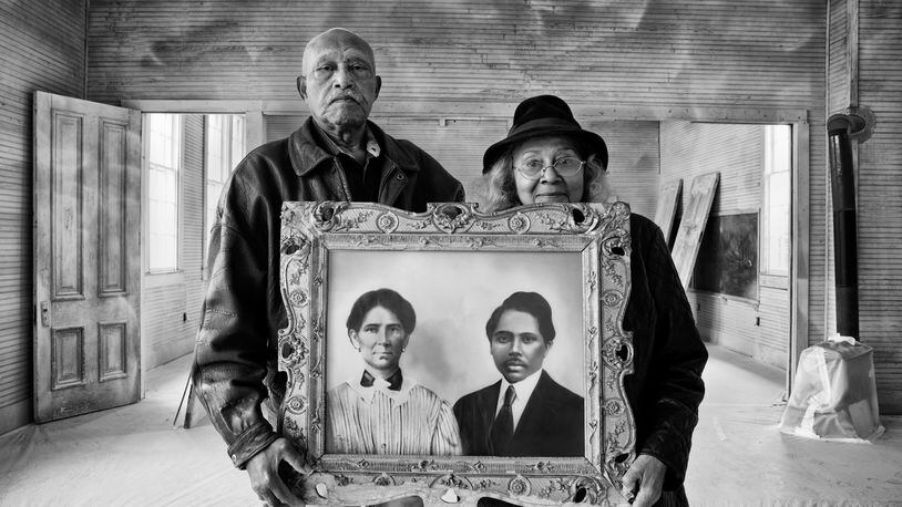 Elroy and Sophia Williams hold a photo of Sophia's grandparents, who were born in slavery but accumulated 1,200 acres of farmland and contributed two acres for a Rosenwald school. They are standing in that structure, the former Hopewell School in Bastrop County, Texas, which Elroy is working to preserve  Photo: Andrew Feiler