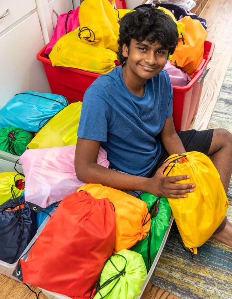 High school junior Akhil Kalva is surrounded by some of the buddy packages he's filled with clothes, toiletries, and other items. Here, he's preparing these bags that will go to foster care children in Fulton County. Akhil lives in Johns Creek and was moved when he learned about the plight of foster children. PHIL SKINNER FOR THE ATLANTA JOURNAL-CONSTITUTION.