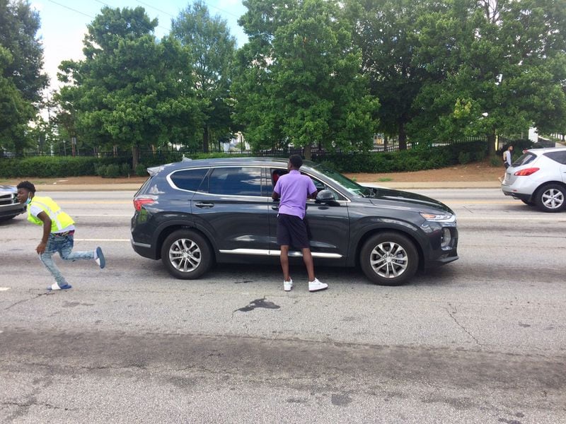 Quanarius Hosch, 15, hurries to get another bottle of water before the light changes at the corner of Northside Drive and Joseph E. Boone Blvd. Photo by BILL TORPY