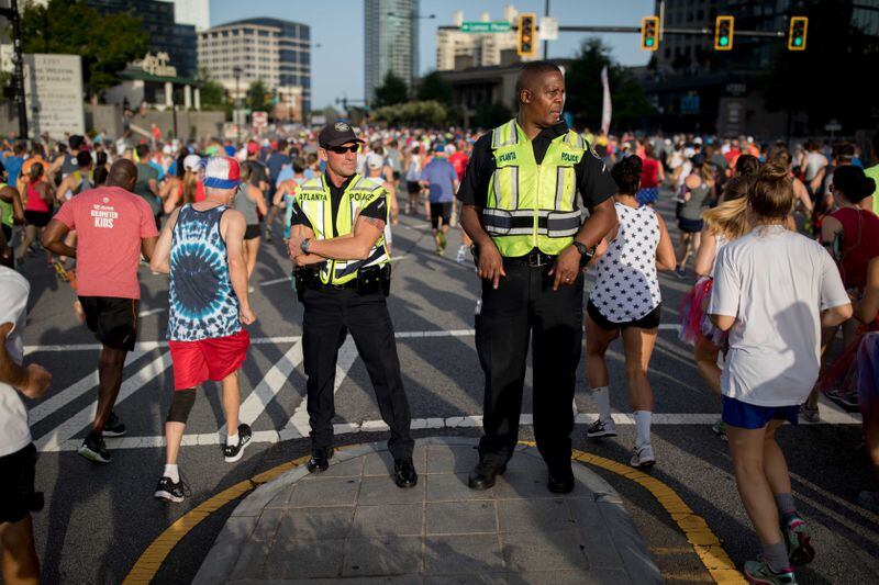 Atlanta police officers keep watch as runners make their way down Peachtree Street during the 48th AJC Peachtree Road Race, Tuesday.   BRANDEN CAMP/SPECIAL