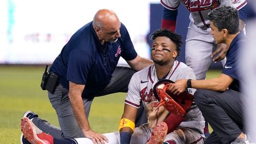Atlanta Braves right fielder Ronald Acuna Jr., sits injured on the field after trying to make a catch on an inside the park home run hit by Miami Marlins' Jazz Chisholm Jr. during the fifth inning of a baseball game, Saturday, July 10, 2021, in Miami. (AP Photo/Lynne Sladky)