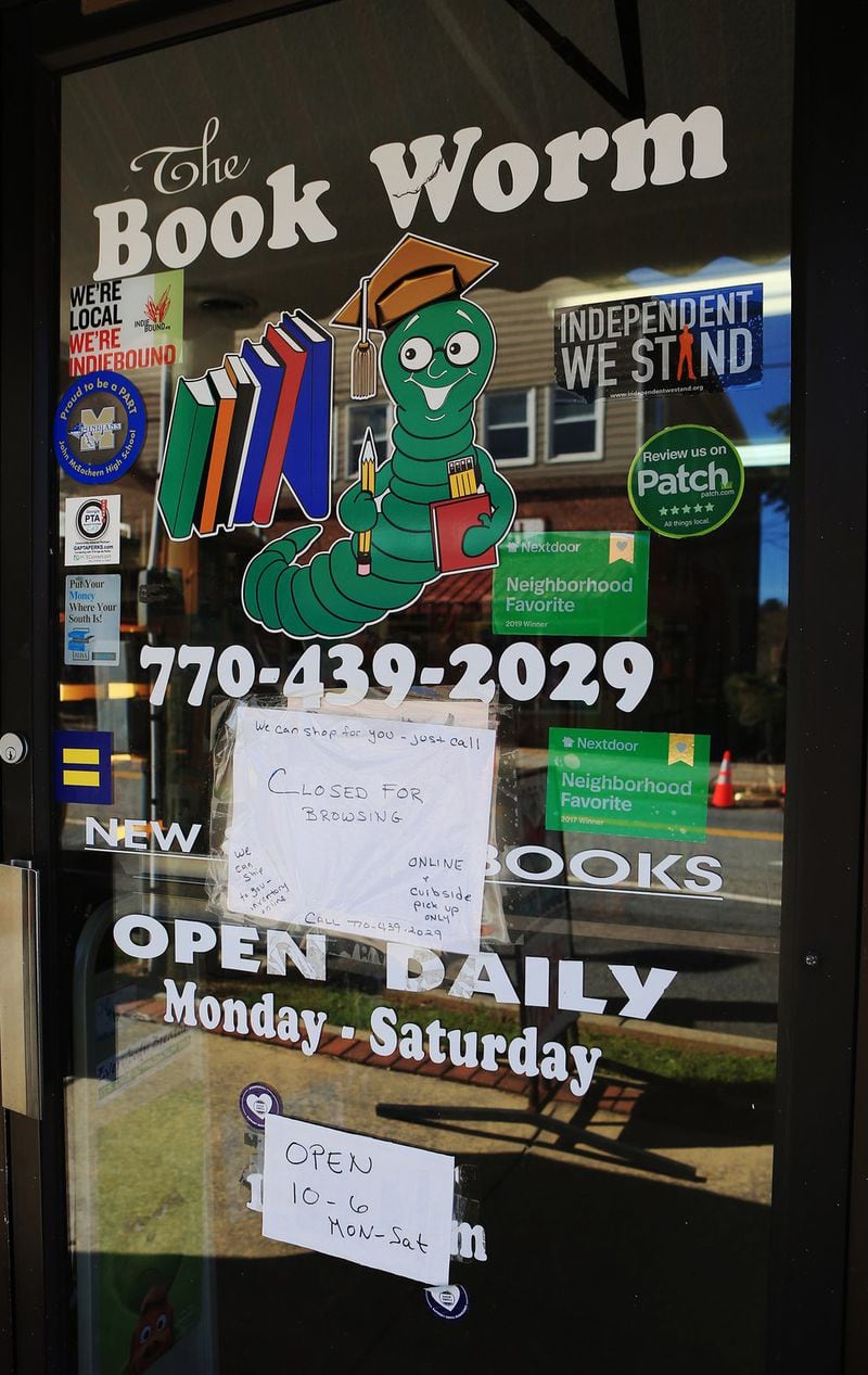 Signs posted on the front door of The Book Worm on Friday, April 3, 2020, in Powder Springs, Georgia. The store is closed to customers due to social distancing concerns; however, books can can be purchased over the phone and picked up or shipped from the store. (Christina Matacotta, for The Atlanta Journal-Constitution)