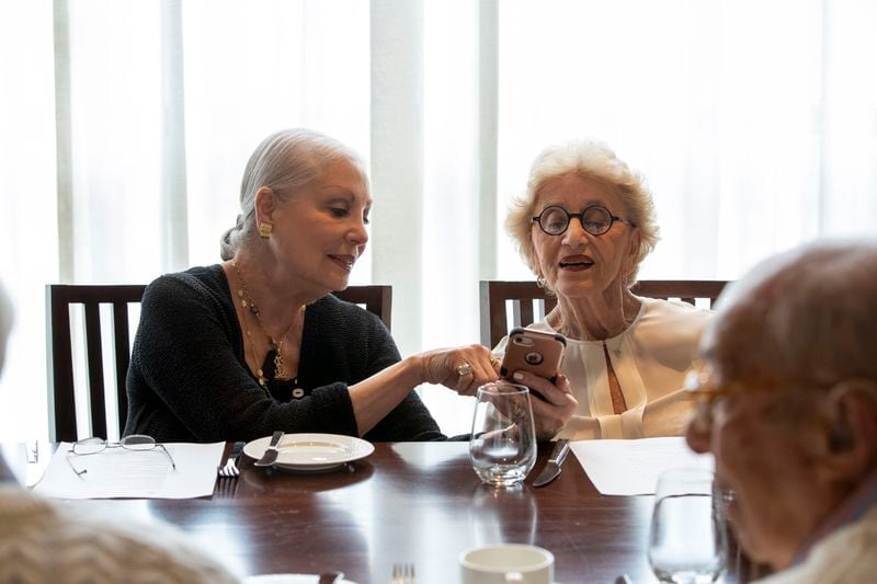 Lennie Swersky, left, shows Marilyn Lavietes, right, a photo on her cellphone during a group lunch date at the Astor Room located inside the St. Regis Hotel in Atlanta’s Buckhead community. (Alyssa Pointer / Alyssa.Pointer@ajc.com)