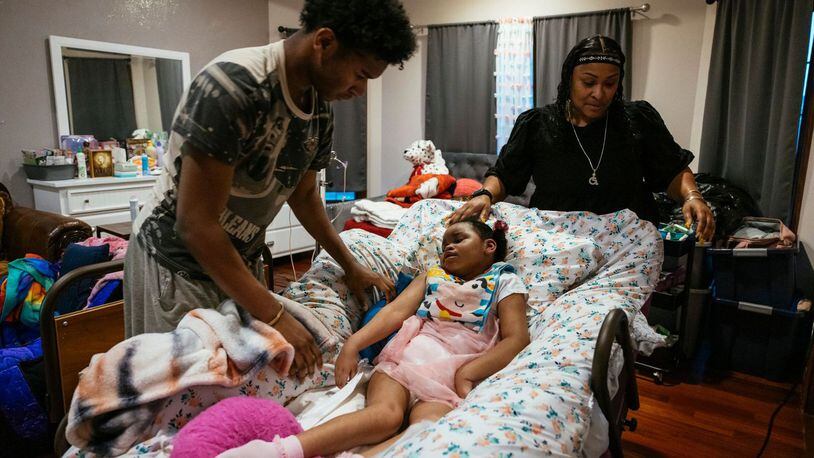 Tyrus Hike (left) helps his mother, Rhonda Jones, administer ibuprofen to Alayna at their home in Crown Point, Indiana. Alayna was injured during her birth and has cerebral palsy. She was recently hospitalized with respiratory syncytial virus, or RSV. (Taylor Glascock for KHN)