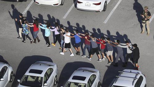 People are brought out of Marjory Stoneman Douglas High School after a shooting at the school on Feb. 14. (Joe Raedle / Getty Images)