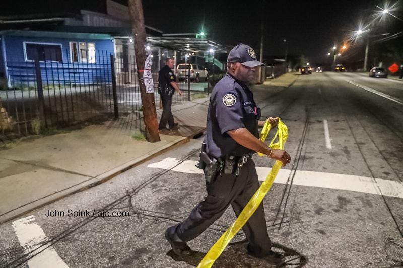 An Atlanta police officer places crime scene tape outside the Ivory club on Whitehall Street in southwest Atlanta. JOHN SPINK / JSPINK@AJC.COM