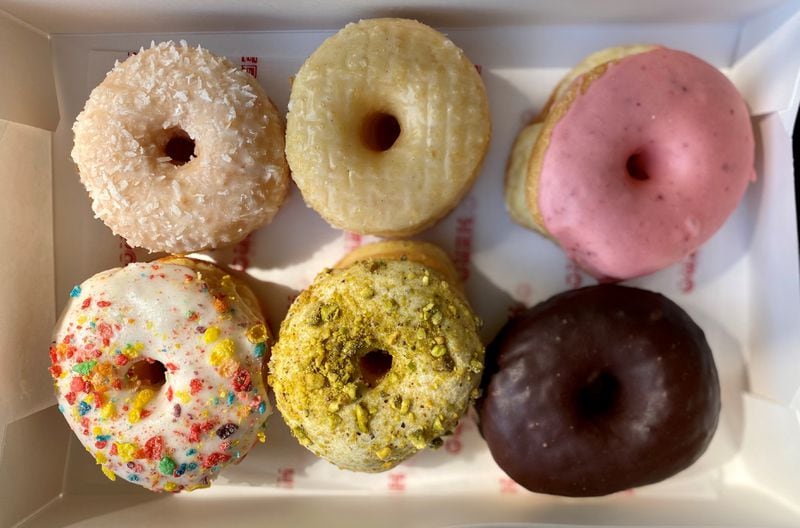 A box of doughnuts from Hero Doughnuts & Buns includes (top row) coconut, original glazed, strawberry glazed; (bottom row) cereal milk, pistachio and chocolate glazed. Wendell Brock for The AJC