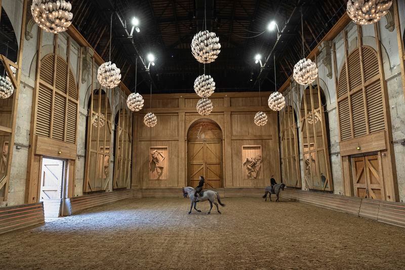 A horsewoman practices with her horse in the stables' riding arena of the royal stables, in Versailles, Thursday, April 25, 2024. More than 340 years after the royal stables were built under the reign of France's Sun King, riders and horses continue to train and perform in front of the Versailles Palace. The site will soon keep on with the tradition by hosting the equestrian sports during the Paris Olympics. Commissioned by King Louis XIV, the stables have been built from 1679 to 1682 opposite to the palace's main entrance. (AP Photo/Aurelien Morissard)