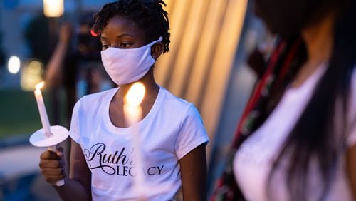 Demi Brandenburg, 12, stares at a candle outside of the National Museum for Civil and Human Rights on Thursday evening August 27, 2020, as part of the “Loved Ones, Not Numbers” campaign to humanize the toll of the current pandemic. BEN GRAY / FOR THE AJC