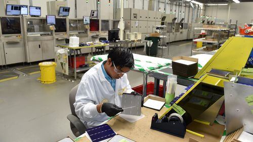 Nishan Kharga performs a quality control inspection of solar cells before they are shipped out for assembly in solar panels. The Suniva manufacturing plant in Norcross runs 24/7 with plans to expand. BRANT SANDERLIN /BSANDERLIN@AJC.COM