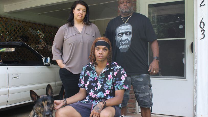 Kameron Gunby, 26, is seated with his mother, Ava Price, and father, Keith Gunby, and dog Kiba, outside his father's home in Kennesaw, Friday, Aug. 7, 2020. Kameron Gunby said he was attacked by three white men Sunday, Aug. 2, 2020, while walking in his neighborhood. The attack sent him to the hospital with a broken nose, fractured check and broken tooth. Police have no suspects.
