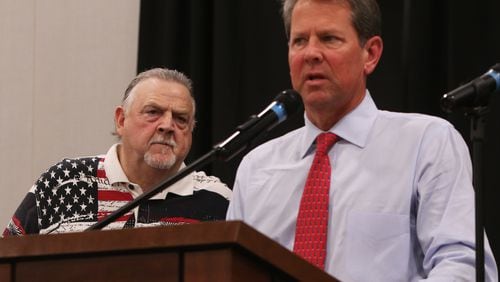 Cobb County Sheriff Neil Warren (left) looks on while Georgia Gov.r Brian Kemp (right) addresses the crowd during the 30th annual Cobb Sheriff's Corn Boilin' at Jim Miller Park in Marietta on Monday. Christina Matacotta/Christina.Matacotta@ajc.com