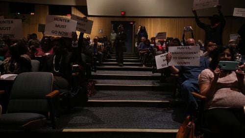 Protesters brought signs to voice their opinions on Tommy Hunter and his comments towards John Lewis to the Gwinnett County Board of Commissioners meeting Tuesday. (HENRY TAYLOR / HENRY.TAYLOR@AJC.COM)