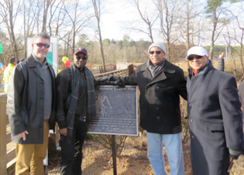 Rich Alvarez of First Tee of Atlanta, DeKalb County Commissioner Larry Johnson, DeKalb County Recreation interim director Marvin Billups and Marvin Hightower of First Tee Atlanta pose next to a sign at a portion of the South River Trail named after former First Lady Michelle Obama. (Photo courtesy of DeKalb County)