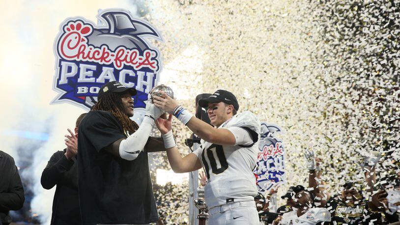 UCF Knights linebacker Shaquem Griffin (18) and quarterback McKenzie Milton (10) celebrate with the trophy after their win against the Auburn Tigers during the Chick-fil-a Peach Bowl at the Mercedes-Benz Stadium Monday, January 1, 2018, in Atlanta. The UCF Knights won 34-27. PHOTO / JASON GETZ