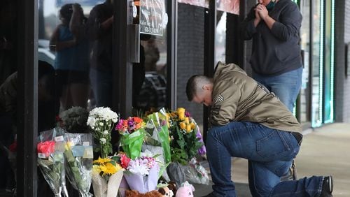 031721 Acworth: U.S. Army veteran Latrelle Rolling (left) and Jessica Lang (right) both pause to pray after dropping off flowers at Young’s Asian Massage where four people were killed on Wednesday, March 17, 2021, in Acworth. At least eight people were found dead at three different spas in the Atlanta area Tuesday by suspected killer Robert Aaron Long.  “Curtis Compton / Curtis.Compton@ajc.com”