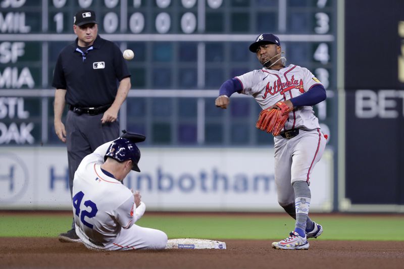 Houston Astros runner Alex Bregman, front left, is out on his slide as Atlanta Braves second baseman Ozzie Albies, right, throws over him while attempting to turn a double play during the sixth inning of a baseball game Monday, April 15, 2024, in Houston. (AP Photo/Michael Wyke)