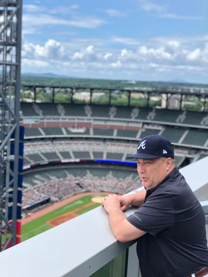 Braves fan Joe Sturniolo, a coach at Westminster Schools, has attended each Braves home opener since his first in 1975, making this year's opener, April 5, 2024, Sturniolo's 50th consecutive opener. Here he stands on a balcony at the Omni Hotel adjacent to Truist Park in 2020. Because of COVID-19, that game was played with no fans in attendance (only cardboard cutouts), so Sturniolo secured a room in the hotel to watch the game and keep his streak alive. (Photo contributed by Joe Sturniolo)