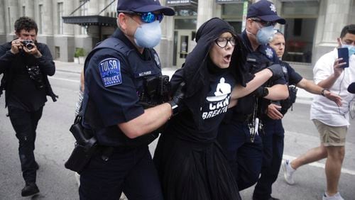 Tulsa Police officers arrest protester for trespassing after she entered the safety barricade of President Donald Trump's campaign rally Saturday June 20, 2020. (Mike Simons/Tulsa World via AP)