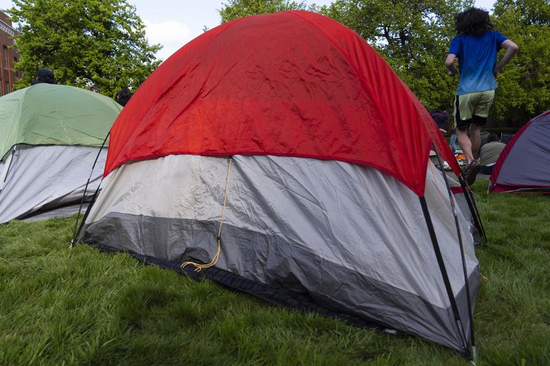 A University of Oregon student jumps to get around tents that were set up on campus to protest the Israel-Hamas war, Monday, April 29, 2024, in Eugene, Ore. (AP Photo/Jenny Kane)