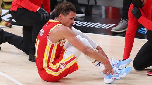 Hawks guard Trae Young is tended to on the floor with a possible ankle injury during the third quarter of Game 3 of the Eastern Conference finals against the Milwaukee Bucks Sunday, June 27, 2021, in Atlanta. (Curtis Compton / Curtis.Compton@ajc.com)