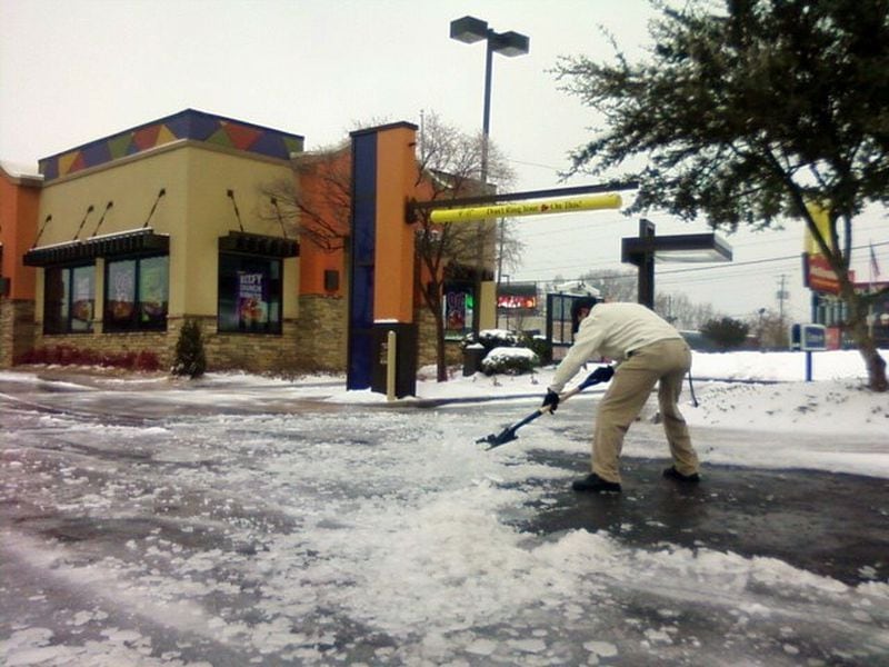 Matt Lindner, manager of the Taco Bell near the intersection of Johnson's Ferry and Lower Roswell roads in Cobb, shovels ice and slush off the parking lot in this  Jan. 11, 2011 file photo.  "Businesswise, it's a curse," he said of the storm. "It's affecting a lot of people's business, and their money." 