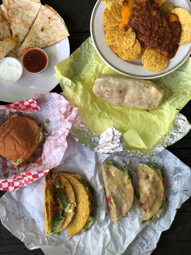 This takeout order from Taco Pete Bistro includes (clockwise from upper left) cheese quesadilla; chili-cheese nachos; a chicken burrito; two soft tacos (beans and cheese; steak); two hard-shell tacos with ground beef; and a taco burger. Wendell Brock for The Atlanta Journal-Constitution
