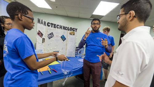 Teens Jared Brown, Dhruvesh Patel and Rafael Montez (l-r blue shirts) explain their nanoscience project to guests during the finale of GSU’s STEM camp for deaf students.