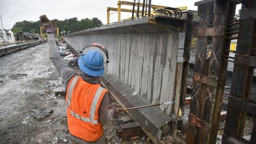Workers simultaneously cut strands of steel rebar that connect giant girders at Standard Concrete Products’ Atlanta plant. The family-owned company produced and delivered 61 bridge girders to the I-85 project over a 15 day stretch. HYOSUB SHIN / HSHIN@AJC.COM