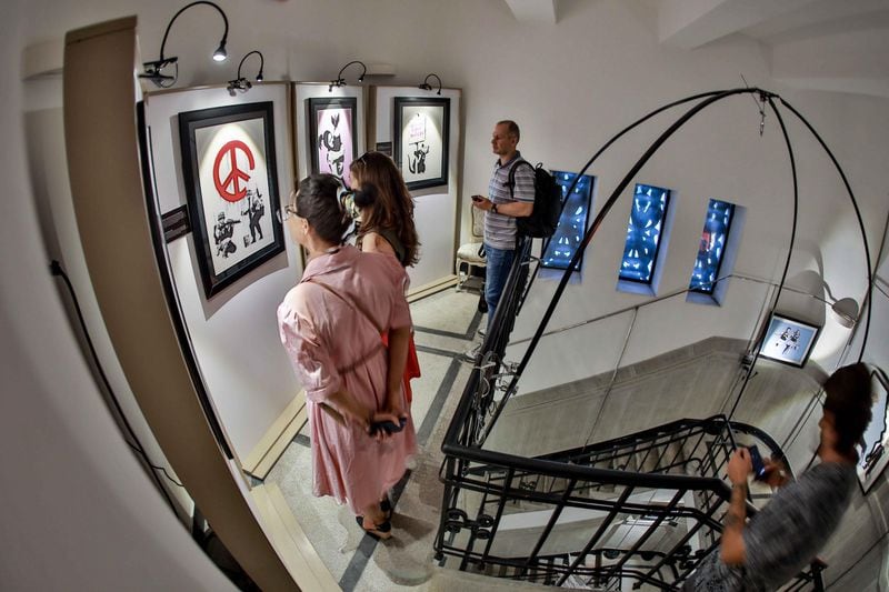 Visitors to an exhibit in Bucharest, Romania, examine an image created by the elusive street artist, Banksy. Courtesy: SEE Global Entertainment
