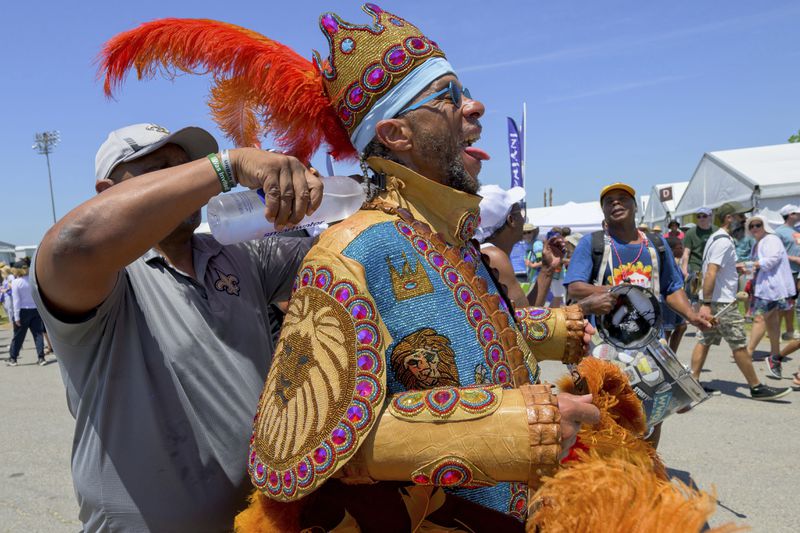 Big Chief Dow "Croco-Dow" Edwards of the Timbuktu Warriors gets cooled off with water in his suit during a procession through the Fair Grounds at the New Orleans Jazz and Heritage Festival in New Orleans, Thursday, April 25, 2024. Black Masking Indian suits can take a over a year to sew and can weigh over 50 pounds. The Black Masking Indians culture is unique to New Orleans beginning in the 1800s but African-Americans have been dancing with drums and feathers for hundreds of years in Louisiana. (AP Photo/Matthew Hinton)