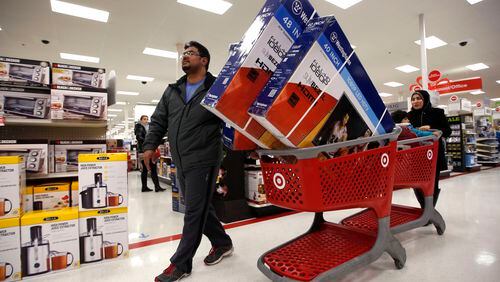 Ahmad Ali and his wife, Ghalzal, of Portland, Maine, look to get in line to pay for three flat-screen televisions while shopping at a Target store just after midnight on Black Friday, Nov. 28, 2014, in South Portland, Maine. (AP Photo/Robert F. Bukaty)