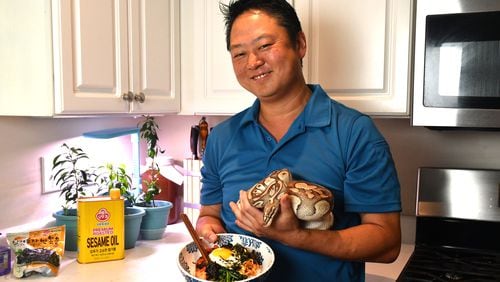Umi Executive Chef Todd Dae Kulper is seen in his home kitchen with a bowl of bibimbap and his pet python, Zeus. Chris Hunt for The Atlanta Journal-Constitution