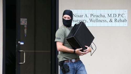 Masked DEA agents raided the office of Dr. Nisar S. Piracha, one of at least six Georgia doctors sent to prison this year for drug violations. BOB ANDRES / BANDRES@AJC.COM