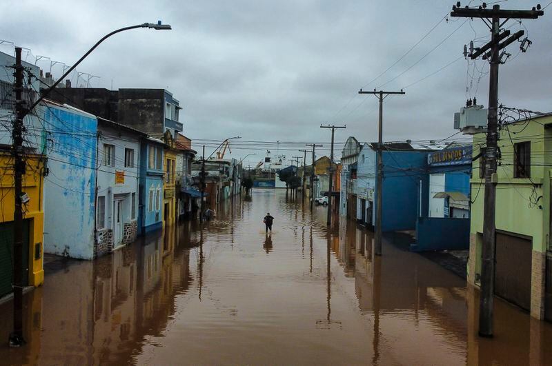 A man wades an area flooded by heavy rains, in Porto Alegre, Rio Grande do Sul state, Brazil, Friday, May 3, 2024. (AP Photo/Carlos Macedo)