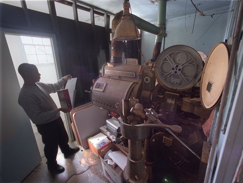 In a photo from 2000, pastor Derrick A. Holloway visits the projection room of the old Ashby Theater, where the vintage projection equipment still rested. In the late 1990s Holloway and his congregation had converted the Ashby into a church home for the New Restoration Christian Cathedral.