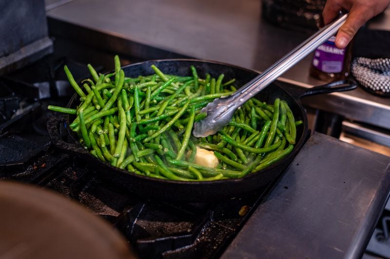 Firefighter Chris Hunter tosses balsamic-glazed green beans with a large knob of butter, drawing on skills developed in a previous job in the kitchen of 8Arm. 