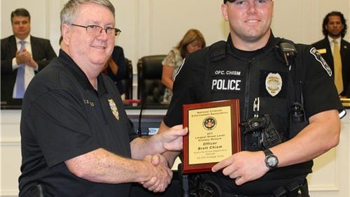 From left, Snellville Police Department Chief Roy Whitehead presents officer Brett Chism with the National Criminal Enforcement Association award for making a bust of 45,000 ecstasy pills at Monday’s Council meeting. Courtesy Snellville