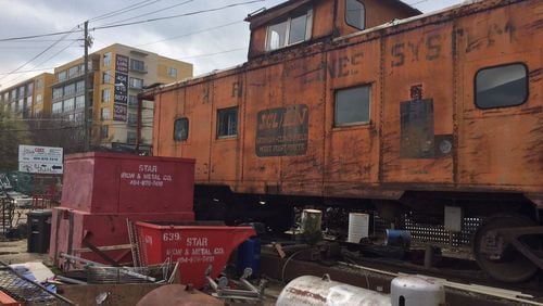 The caboose at Star Iron and Metal will stay, but all the junk is going as the property may very well end up looking like the apartment complex looming in the background. Bill Torpy / btorpy@ajc.com