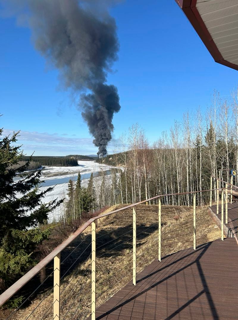 Smoke rises after a Douglas C-54 Skymaster plane crashed into the Tanana River outside Fairbanks, Alaska, Tuesday, April 23, 2024. The plane took off in the morning from Fairbanks International Airport. It crashed about 7 miles (11 kilometers) from there and "slid into a steep hill on the bank of the river where it caught fire," according to Alaska State Troopers. (Gary Contento via AP)