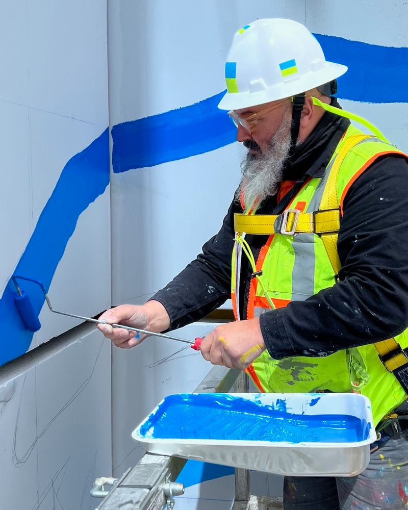 Joe Dreher works on the mural on the side of the Midtown Union building.